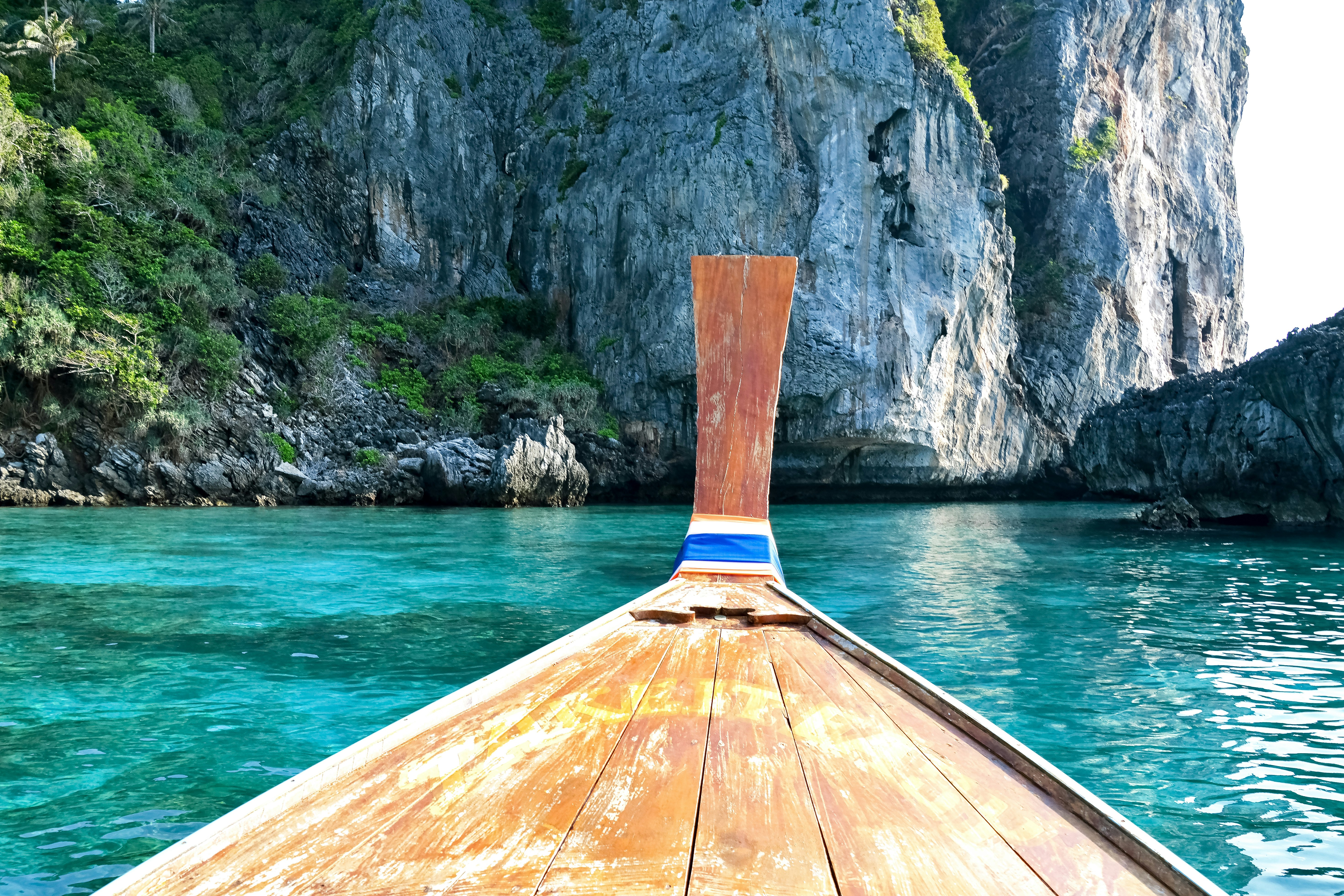 brown wooden boat on water near mountain during daytime